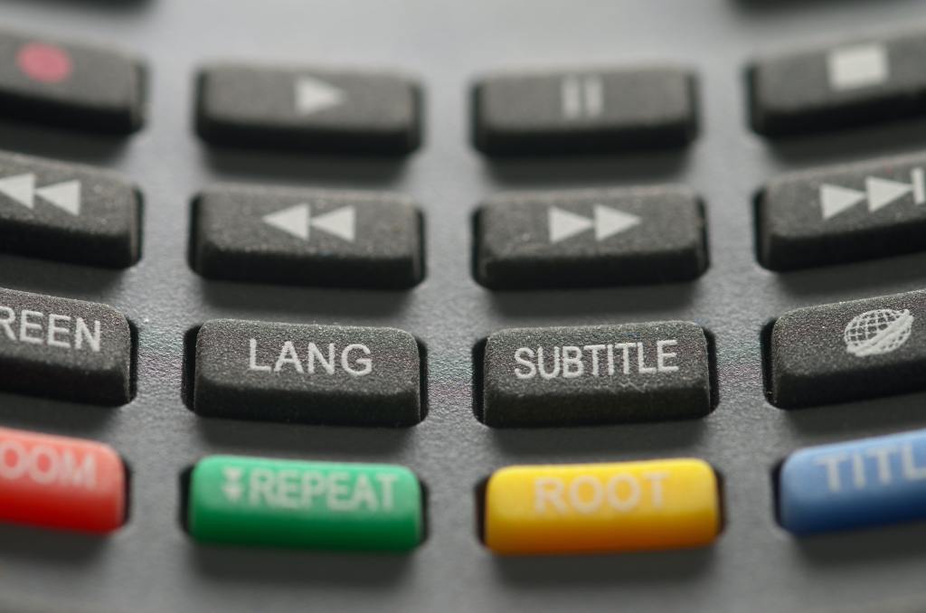 This shows a remote control with buttons that say "LANG" and "SUBTITLE"